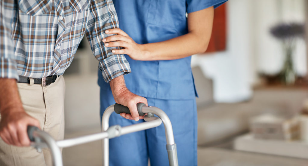 Nurse assisting elderly patient with walker 