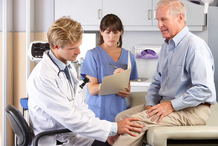 Male Doctor Examining Male Patient With Knee Pain