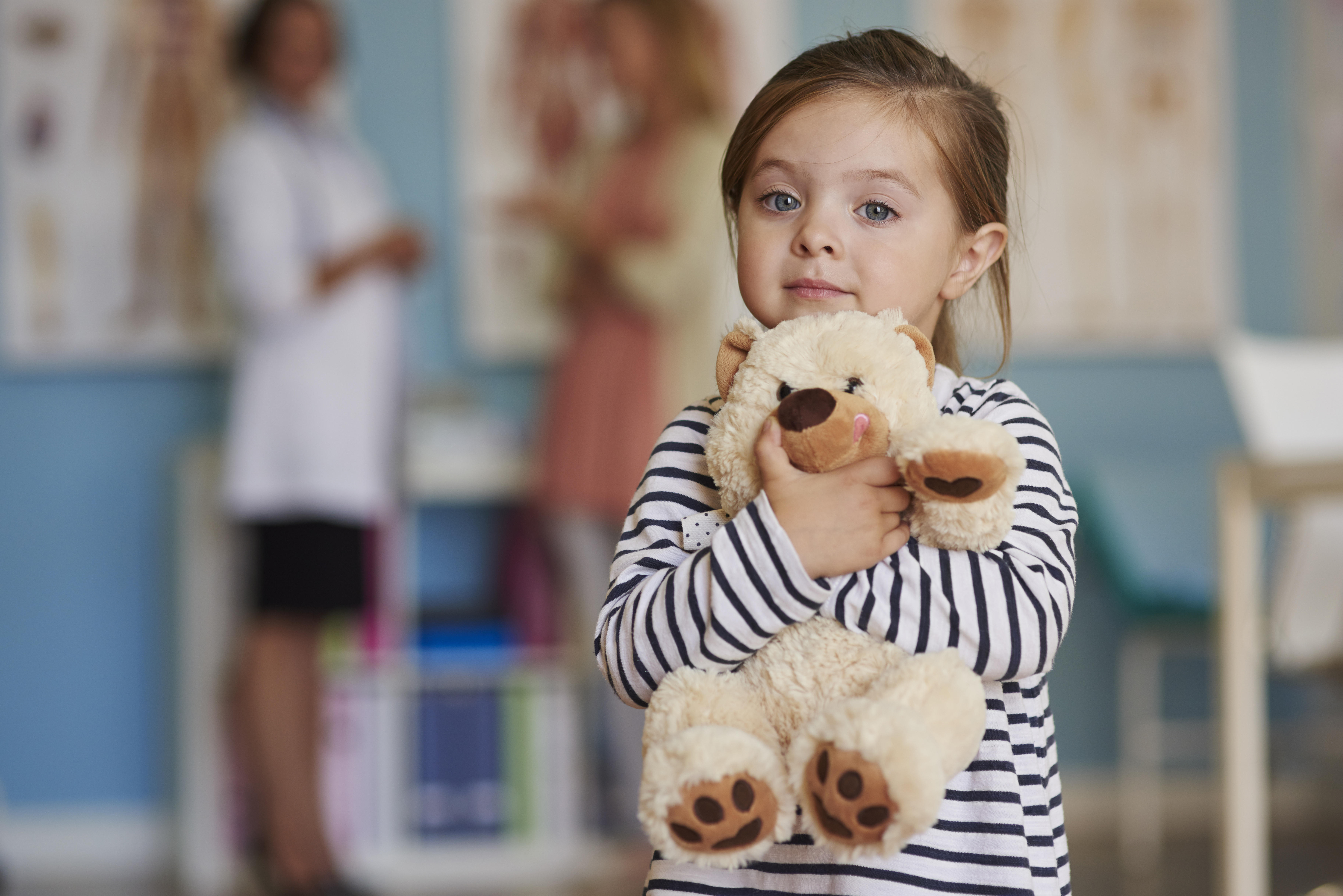 Child holding stuffed animal in hospital setting